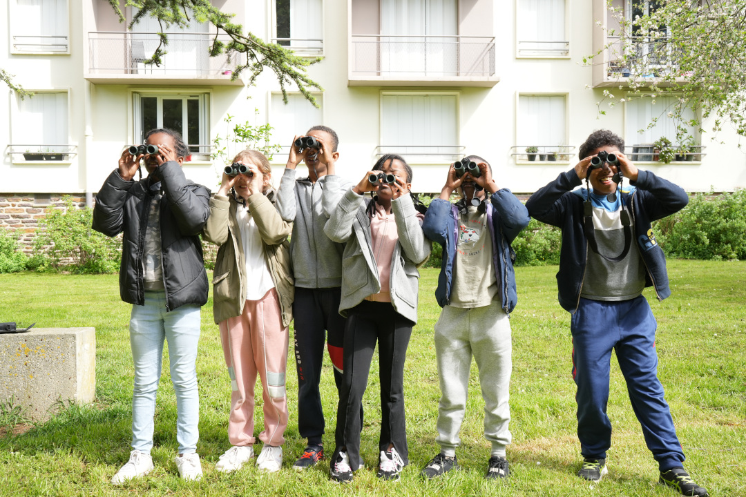 Groupe de six enfants en train de regarder au loin avec des jumelles