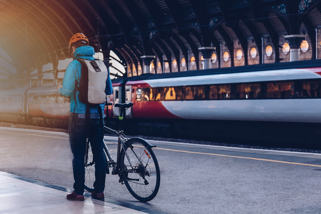 Personne avec son vélo sur le quai d'une gare, un train en fond