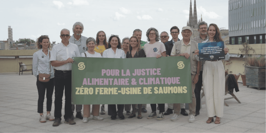 rassemblement du collectif en opposition à Pure Salmon avec une banderole "Pour la justice alimentaire et climatique zéro ferme-usine de saumons"