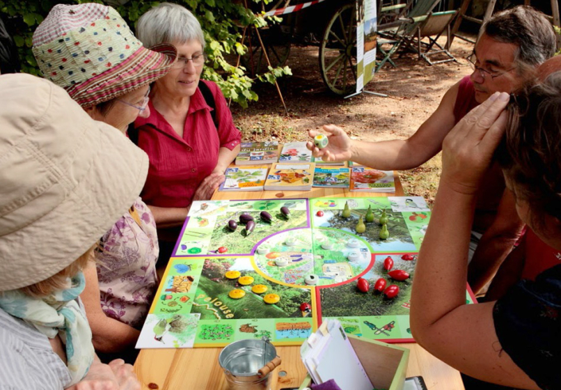 un plateau de jeu est au centre de la photo avec des personnes install&eacute;es autour.