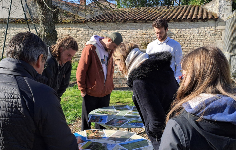 Des personnes regardent des photos de paysages et de jardins posées sur une table.