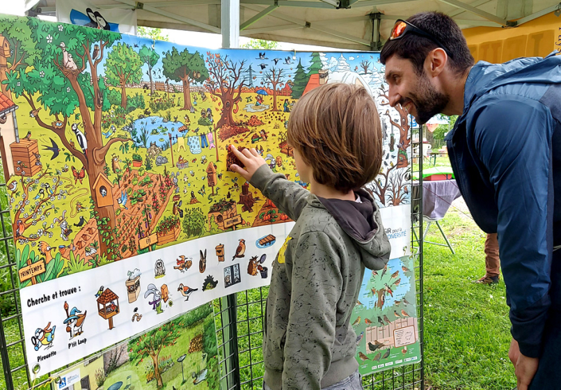 Un enfant regarde une affiche montrant un jardin et cherche des &eacute;l&eacute;ments de cet image, comme des nichoirs pour les oiseaux, un compost, etc.