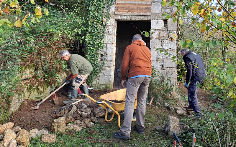 Trois personnes ont des outils pour &eacute;taler de la terre et constuire un muret de pierre s&egrave;che pour la faune